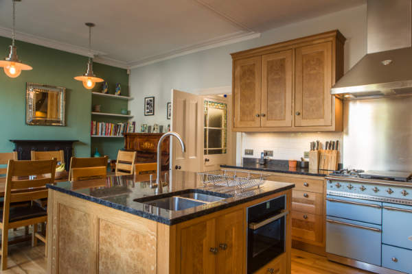Wide view of kitchen showing range on right and the sink and combi oven in the kitchen island