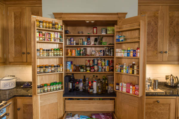 Larger cupboard with doors open showing shelves for ingredients, deep drawers, and spice racks on the reverse of the doors.