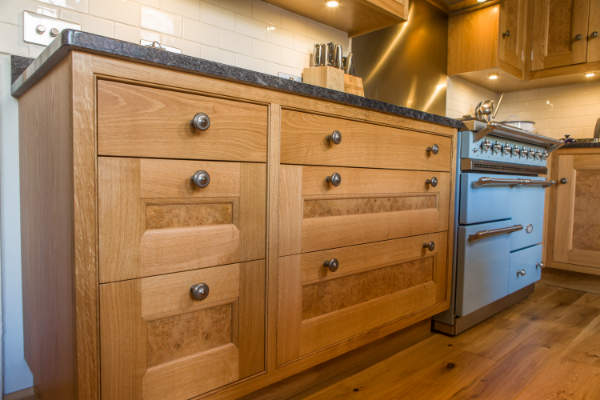 Cabinets with Drawers that have pewter handles and burr oak veneers on the panels. The cabinets have granite worktops