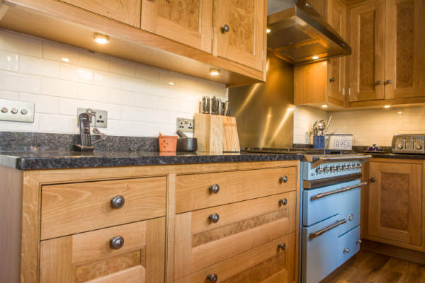 Run of cabinets showing the granite worktops, to the right is a duck egg blue Lacanche range cooker