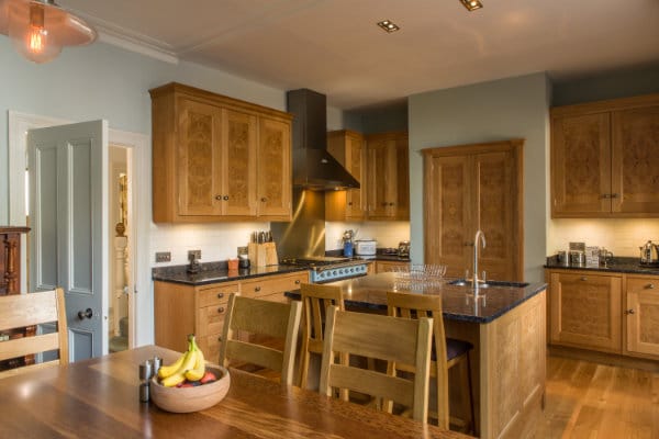 Kitchen with Oak cabinets & cupboards, granite worktops, kitchen island and handmade oak trestle table